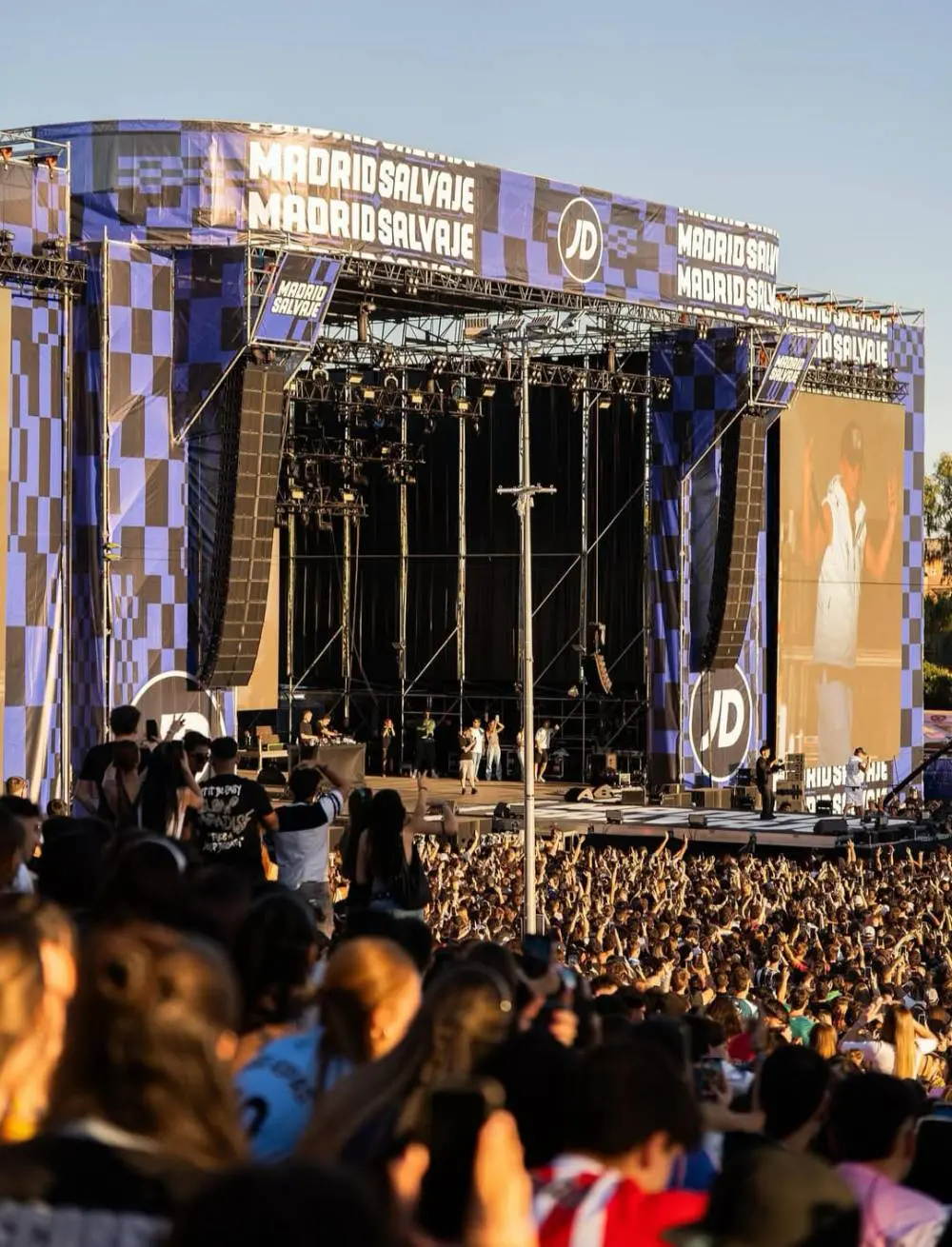 Escenario del festival con la marca JD en las pantallas y los laterales, y el público delante.
