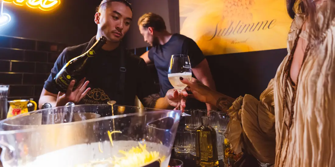 Servicio del espumoso en la barra, con invitados alrededor.