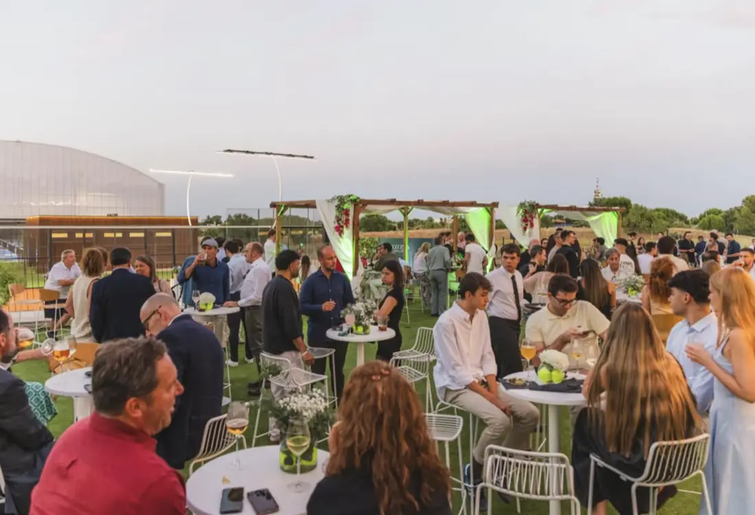 Invitados en la terraza durante la celebración, con mesas altas y vistas al club.
