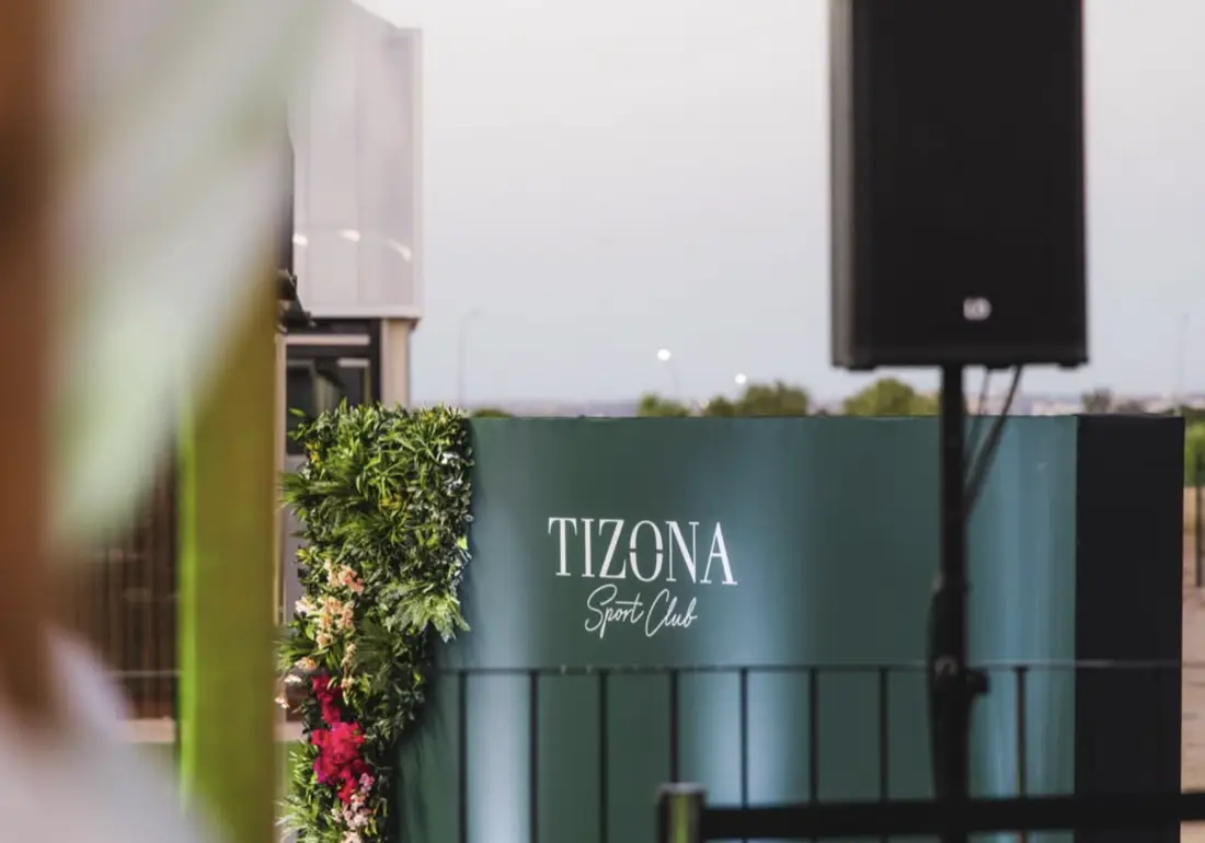 Rótulo de Tizona en la terraza, con decoración floral y equipo de sonido.