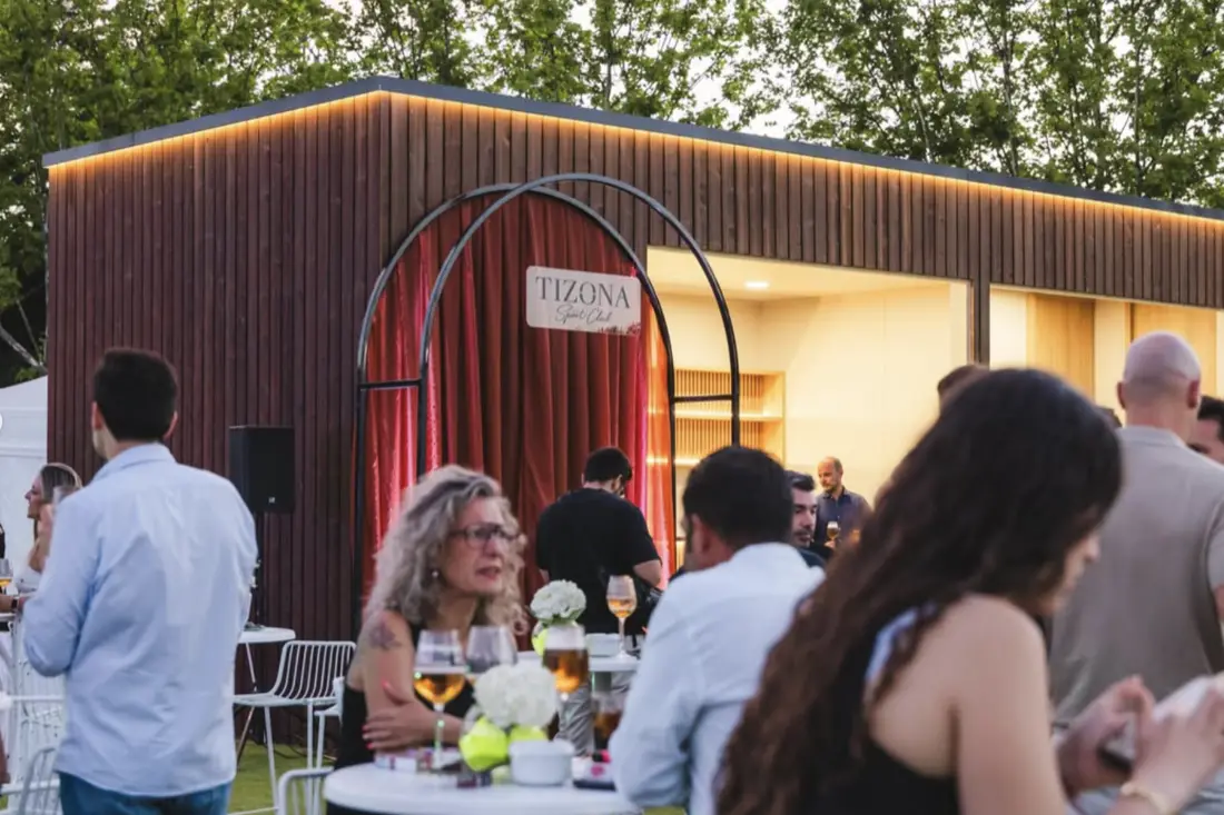 Acceso al edificio del club durante la inauguración, con el arco de entrada y los invitados en la terraza.